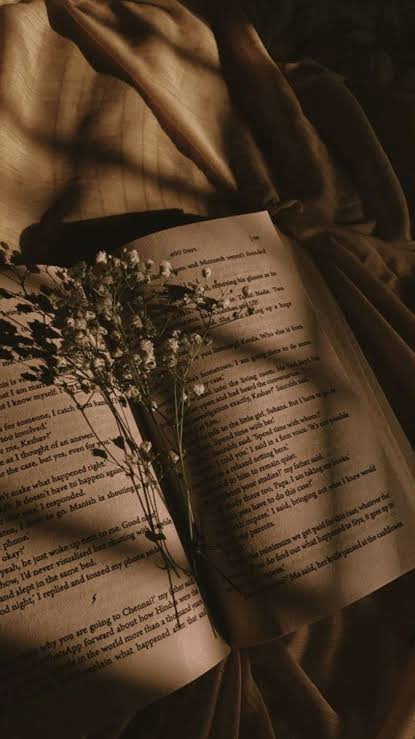 An open book with delicate flowers in warm candlelight